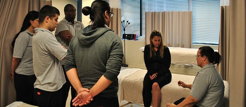 Teacher with students in a massage training session. If you're looking for Massage programs in Vienna, call AMBI!
